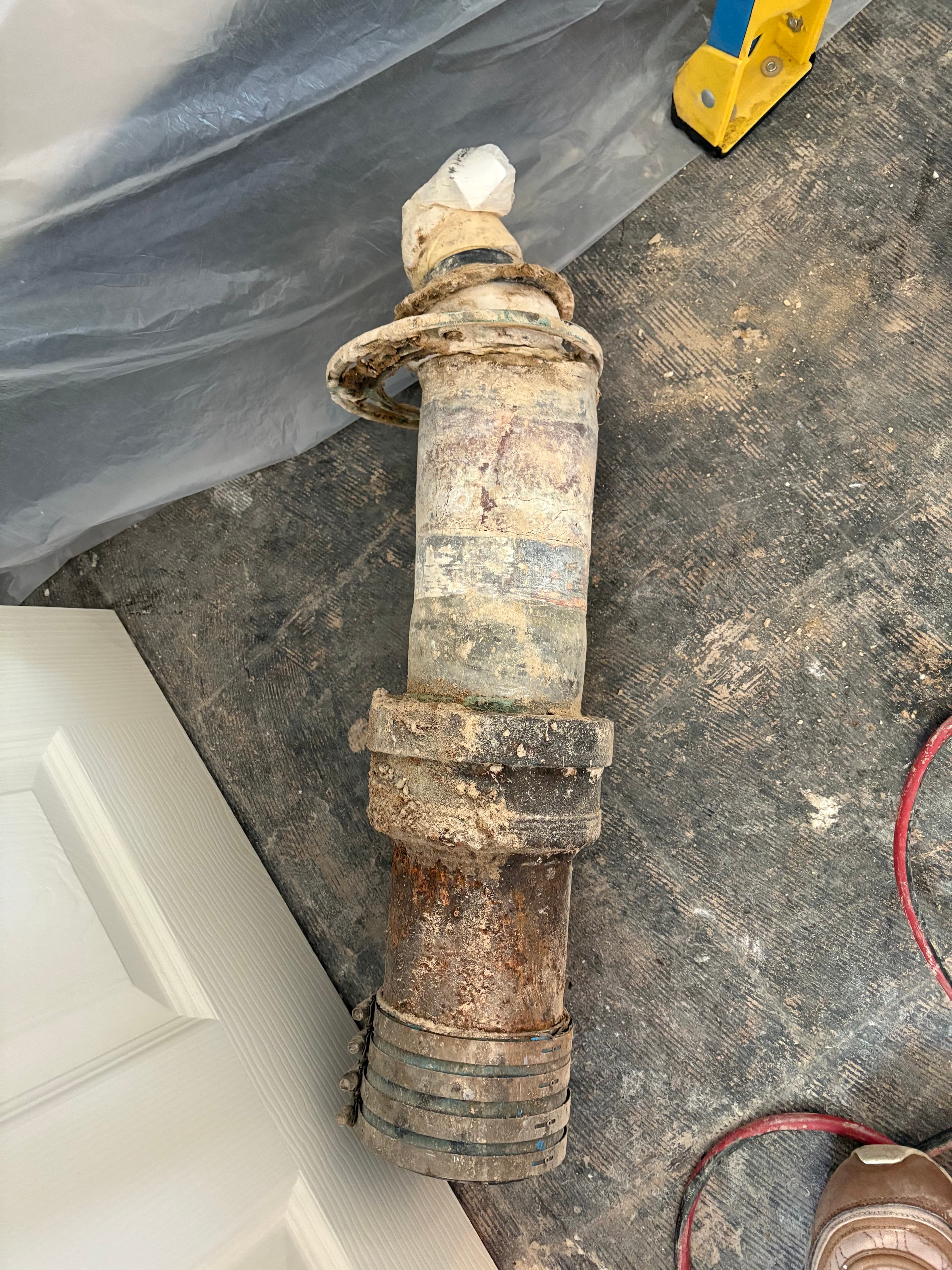 The extracted drain pipe after removal, showing severe corrosion and deterioration